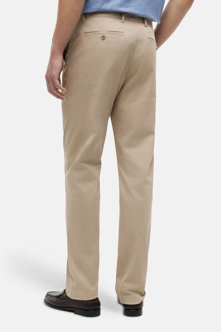Chino beige de TOMMY HILFIGER, vue arrière avec bouton sur la poche, porté avec une chemise bleue et des mocassins marron.