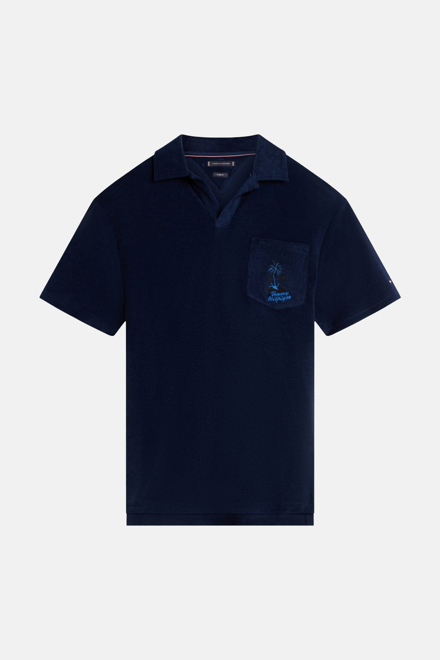Polo en tissu éponge bleu de TOMMY HILFIGER avec col ouvert et poche poitrine avec palmier brodé et logo de la marque.