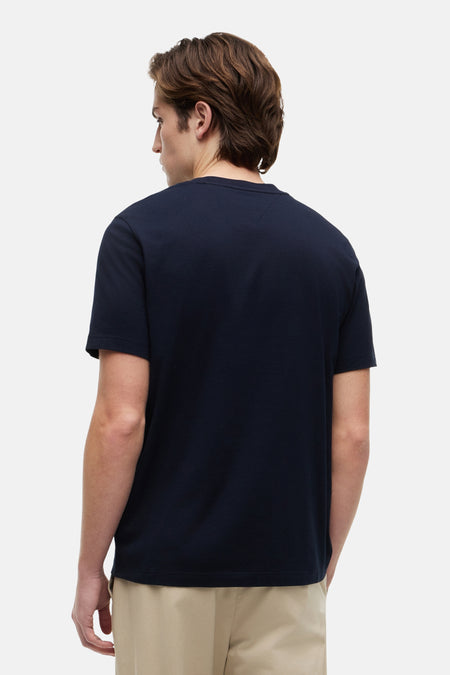 T-shirt bleu foncé à manches courtes de TOMMY HILFIGER, dos visible, porté par un homme avec un pantalon beige.