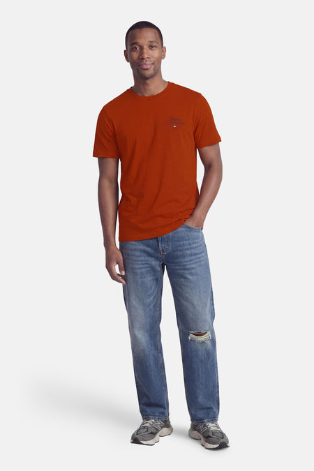 Oranje korte mouwen T-shirt van TOMMY HILFIGER met klein logo op borst, gedragen met blauwe jeans en sneakers, front view