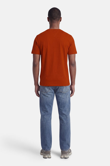 Oranje korte mouwen T-shirt van TOMMY HILFIGER, achterzijde, gladde stof, model draagt blauwe jeans en grijze sneakers