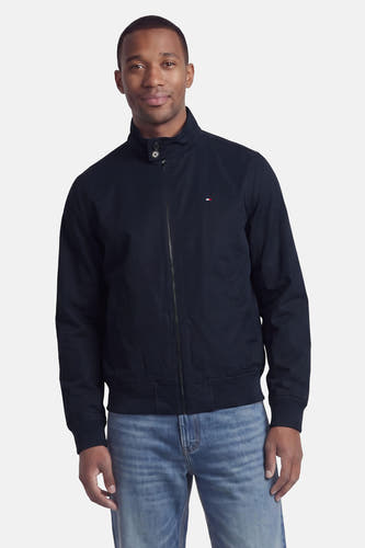 Donkerblauwe korte jas van TOMMY HILFIGER, met rits, opstaande kraag en klein logo op borst, gedragen met lichtblauwe jeans, front view.