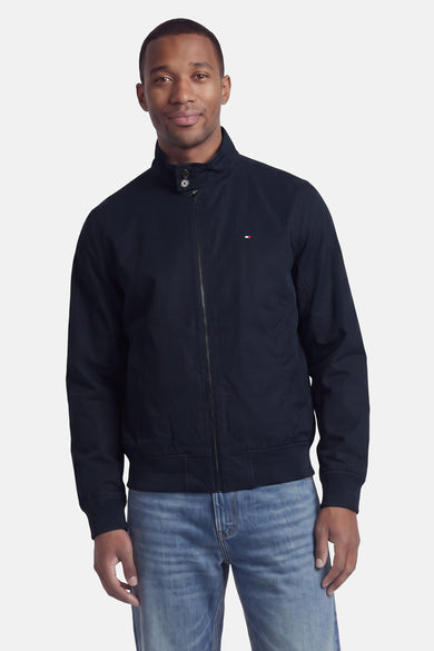 Donkerblauwe korte jas van TOMMY HILFIGER, met rits, opstaande kraag en klein logo op borst, gedragen met lichtblauwe jeans, front view.