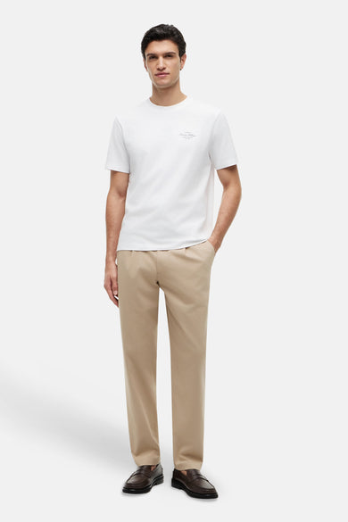 Witte korte mouwen T-shirt van TOMMY HILFIGER met klein logo op borst, gedragen met beige broek en bruine loafers, front view