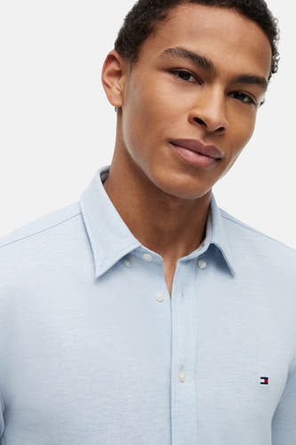 Lichtblauw overhemd van TOMMY HILFIGER, met witte knopen en klein logo op borst, close-up van model
