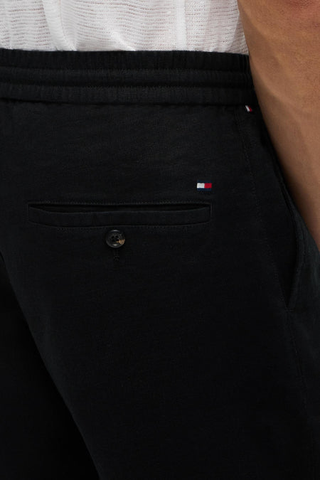 Bermuda noire de TOMMY HILFIGER, avec une poche à rabat et un petit logo de marque.