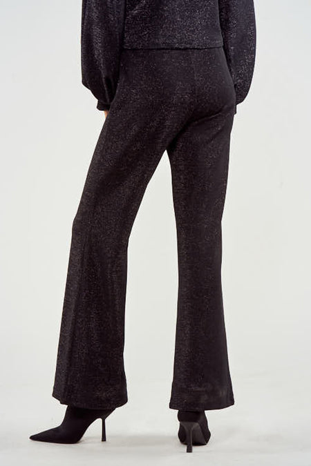 Pantalon noir de NOOR BY NORA GHARIB, avec des jambes qui tombent et associé à des bottines noires.