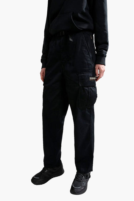 Zwarte cargobroek van NAPAPIJRI, met een cargo zak op het been, gecombineerd met een zwarte hoodie en zwarte sneakers.
