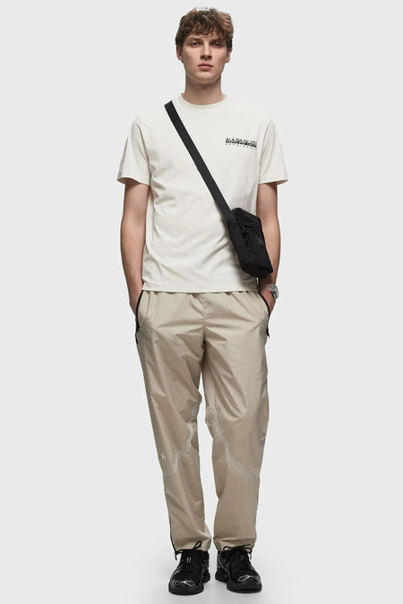 Ecru T-shirt van NAPAPIJRI, met korte mouwen en een klein logo op de borst, gedragen met een zwarte crossbody tas en beige broek.
