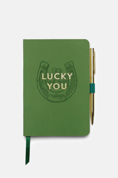 Cadeau vert de DESIGNWORKS INK, avec un fer à cheval en or et une plume dorée avec des détails verts.