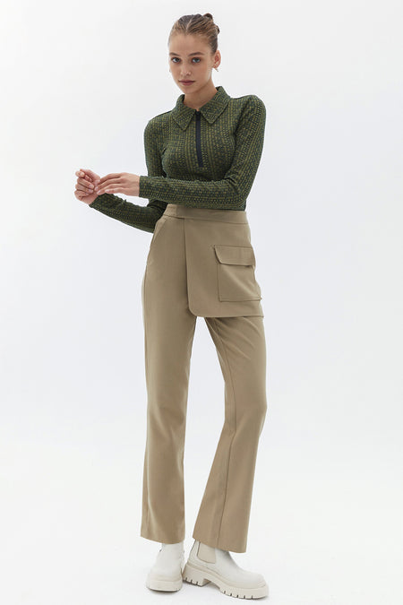 Pantalon beige d'OXXO, avec une poche décorative et une fermeture éclair à l'avant, associé à des bottes blanches.