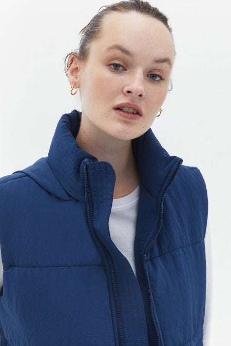 Gilet de corps bleu d'OXXO, avec col montant et fermeture à glissière.