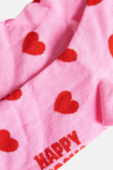 Roze sokken van Happy Socks®, met rode hartjes en het woord "HAPPY" erop geborduurd.

