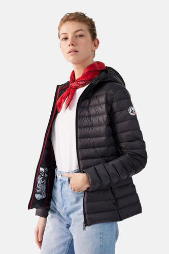 Zwarte regenjas van JOTT, met capuchon en rode details aan de binnenkant, gedragen met een wit t-shirt en blauwe jeans.
