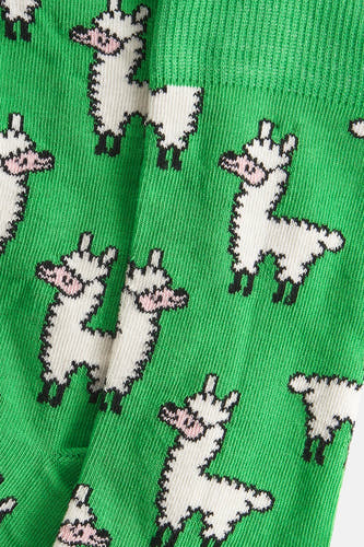 Groene sokken van Happy Socks® met pixelachtige witte lama's als patroon, een close-up.
