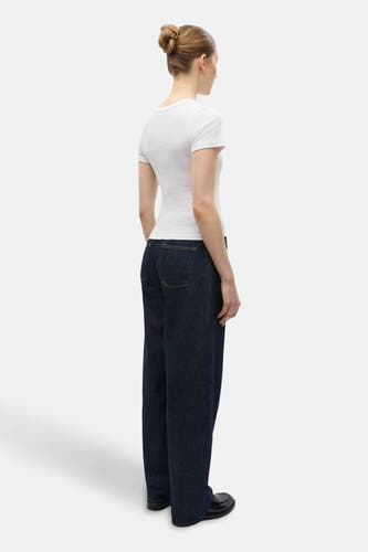 T-shirt blanc à manches courtes d'ENVII, avec col rond, associé à des jeans foncés et des chaussures noires.