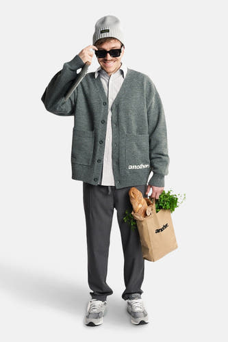 Veste grise d'ANOTHER COTTON LAB, portée avec un chemisier rayé, des pantalons gris, une beanie et un sac de courses.