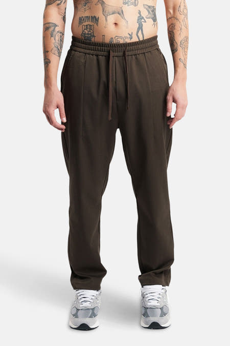 Bruine broek van ANOTHER COTTON LAB, met trekkoord en gedragen met grijze sneakers.

