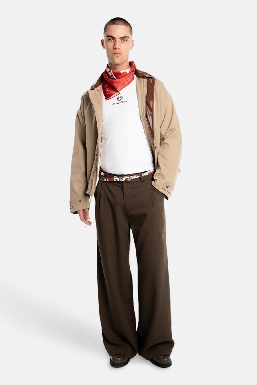 Bruine broek van ANOTHER COTTON LAB, met wijde pijpen, gecombineerd met een wit T-shirt, rode bandana en beige jas.