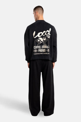 Zwarte sweater van ANOTHER COTTON LAB, met grote witte opdruk op de rug, gecombineerd met wijde zwarte broek.
