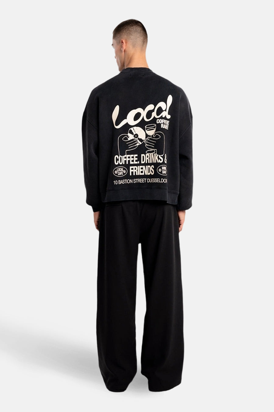 Zwarte sweater van ANOTHER COTTON LAB, met grote witte opdruk op de rug, gecombineerd met wijde zwarte broek.
