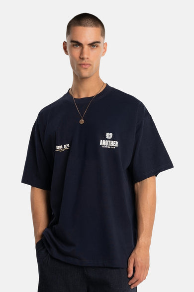 T-shirt bleu à manches courtes de ANOTHER COTTON LAB, avec logo sur la poitrine et une chaîne dorée.