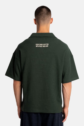 Polo verte à manches courtes de couleur verte de ANOTHER COTTON LAB, avec un imprimé texte au dos.