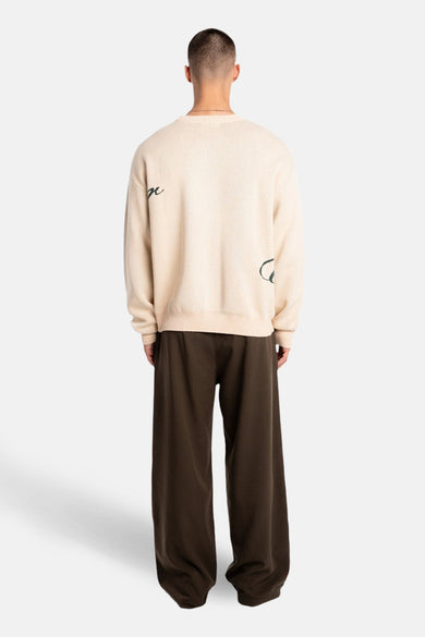 Pull beige à col rond de ANOTHER COTTON LAB, avec un imprimé graphique au dos et un pantalon long, ample et marron.