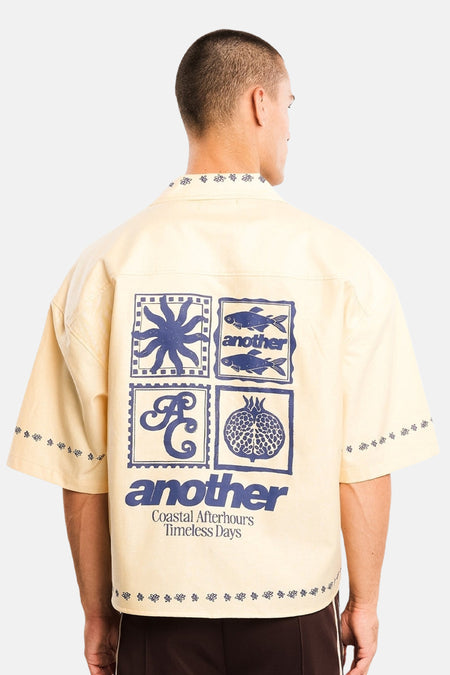 Geel katoenen overhemd met korte mouwen van ANOTHER COTTON LAB, rugzijde met blauwe grafische print en bloemenmotief aan kraag en mouwen, model in lifestyle shot