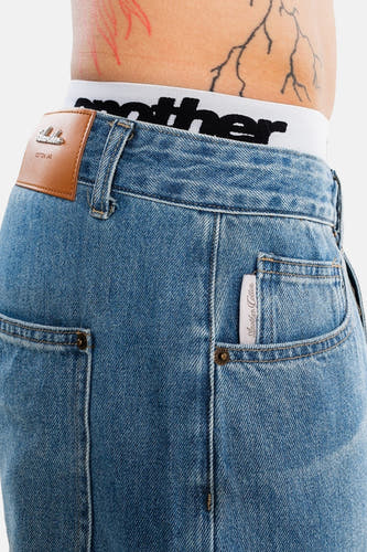 Lichtblauwe denim jeansshort met bruin leerlabel van ANOTHER COTTON LAB, detail van achterzak en taille, close-up.