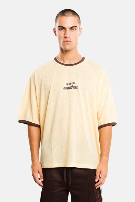 Gele oversized T-shirt met korte mouwen van ANOTHER COTTON LAB, bruine bies, klein logo op borst, front view, model draagt donkere broek