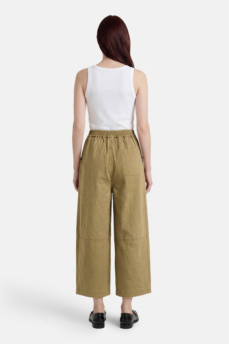 Groene chino broek van ADORE, wijde pasvorm met elastische taille, achterzak en patchdetails, achterzicht model in wit topje en zwarte loafers