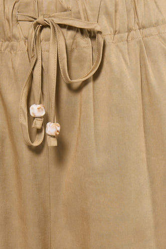Beige damesbroek met elastische taille van ADORE, detail van strik met marmeren knopen, close-up voorzijde
