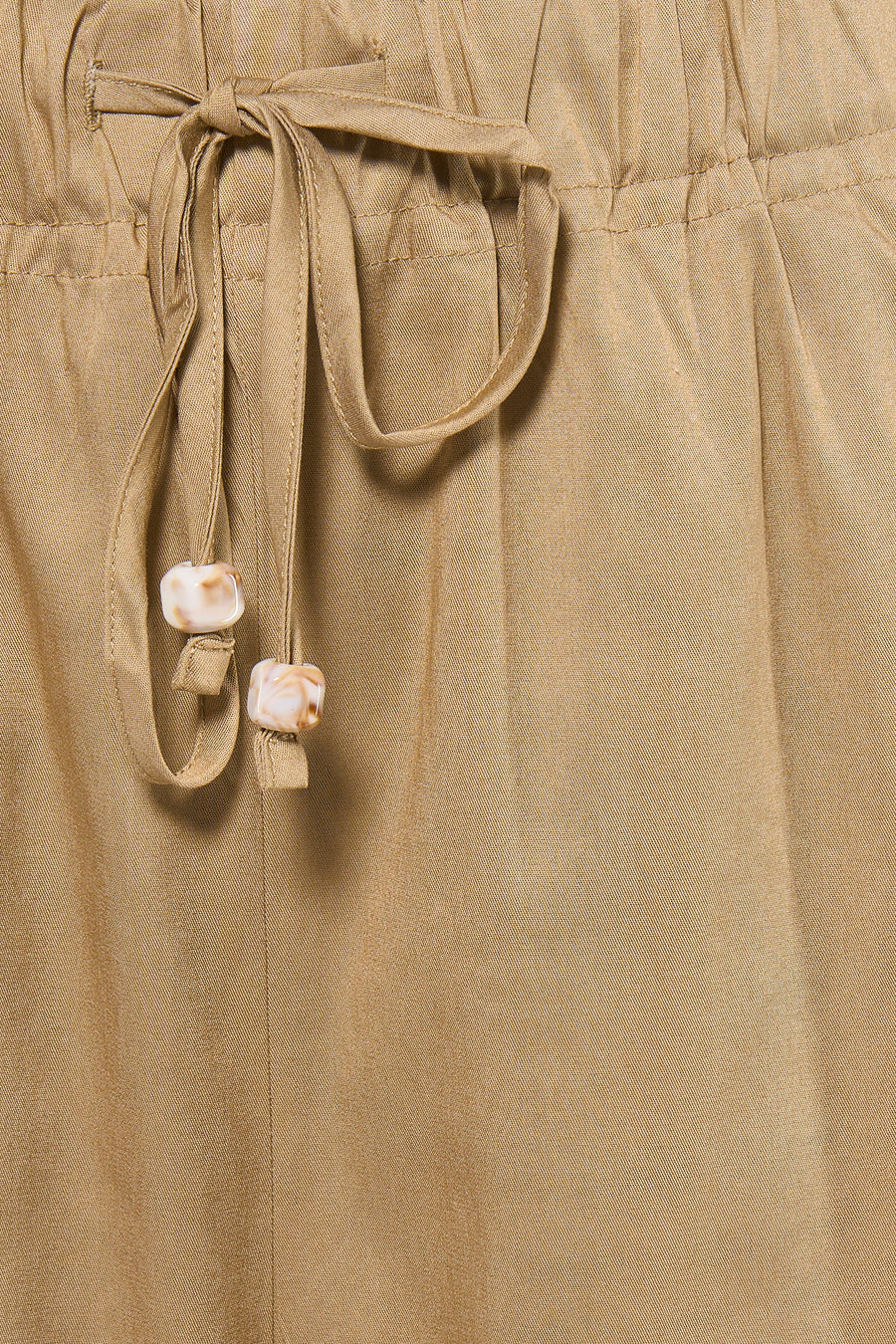 Beige damesbroek met elastische taille van ADORE, detail van strik met marmeren knopen, close-up voorzijde