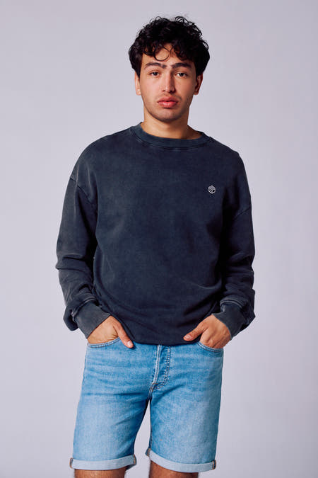 Gilet noir avec col rond de Rock Werchter 50, avec petit logo, associé à des shorts en denim.