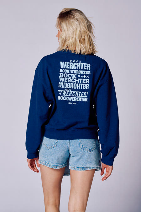 Blauwe sweater van Rock Werchter met logo-opdruk op de achterkant, gecombineerd met denim shorts.
