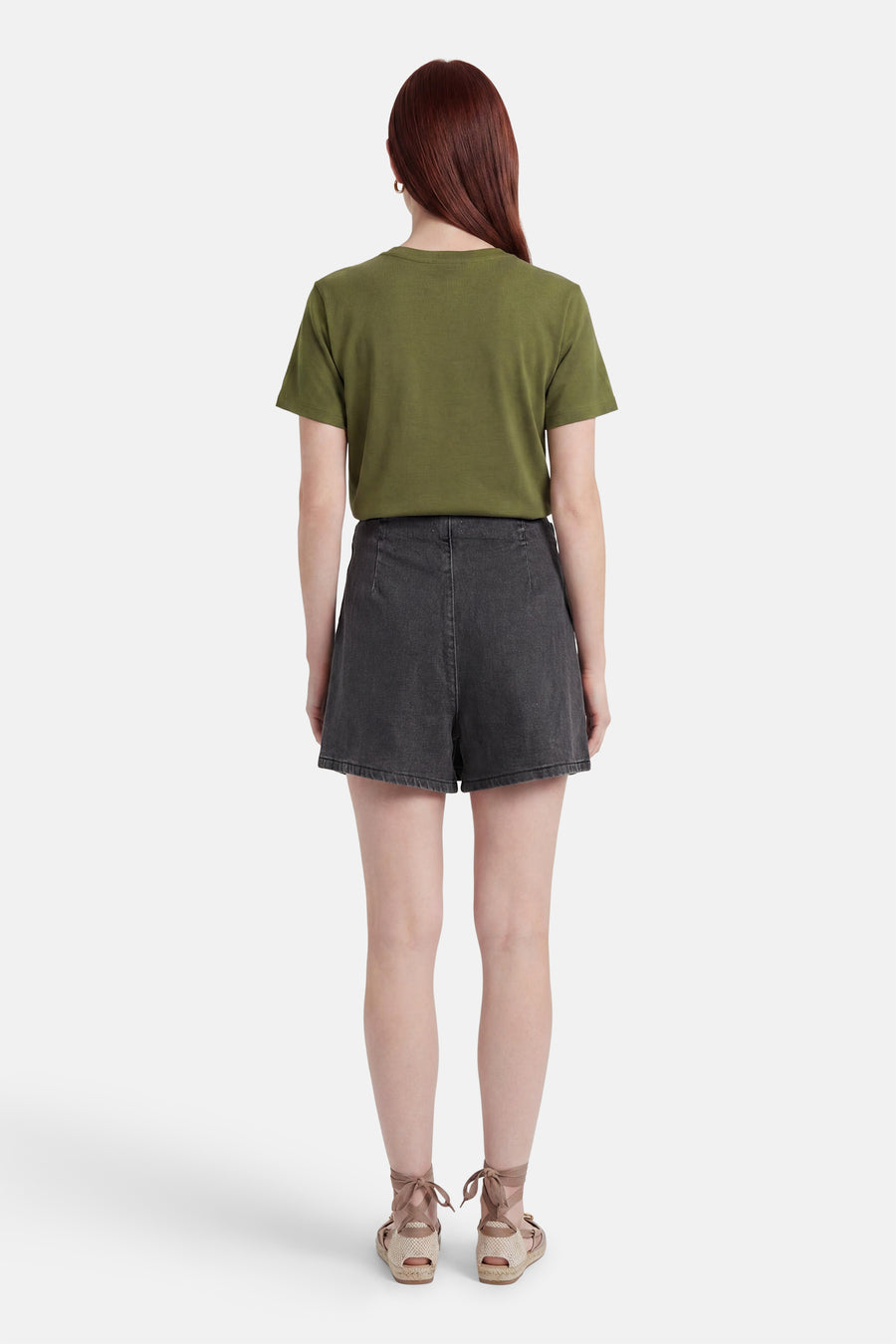 Zwarte denim skort van HAILYS, achteraanzicht gedragen met een olijfgroen T-shirt en espadrille sandalen.