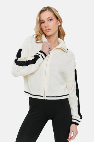 Gilet écru de TALLY WEIJL avec des manches longues et des rayures noires, porté avec un pantalon noir.