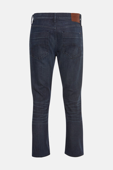 Jean slim fit bleu de denim, de TOMMY JEANS, avec des poches arrière et une étiquette en cuir brun.
