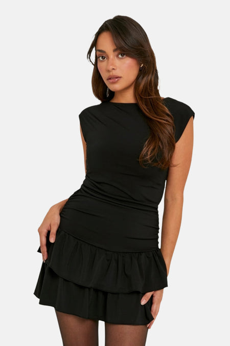 Een vrouw in een zwarte jurk met een gerimpelde taille en een gelaagde rok.