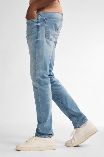 Slim fit denim jeans van Petrol Industries, in een lichte wassing, gedragen met witte sneakers.
