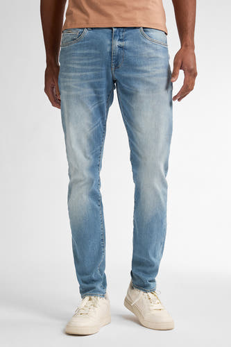Slim fit jeans van Petrol Industries, met lichte wassing en beige sneakers.
