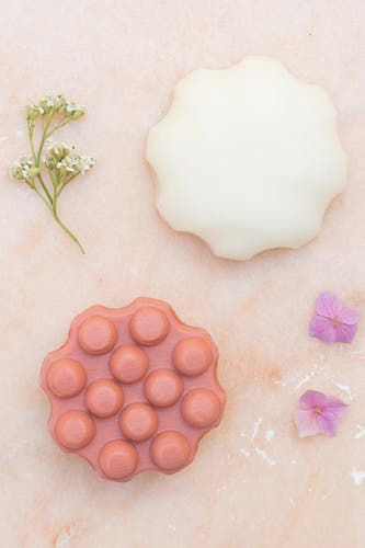 Shampoo bar in de kleur van zoete meloen van WONDR CARE, met bloemendetails voor de styling.