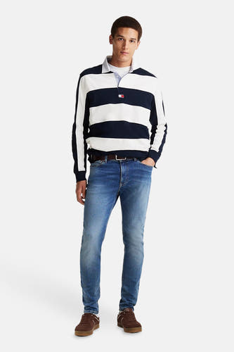 Jean skinny en denim Tommy Jeans, avec une légère usure, associé à des chaussures de cuir marron et un pull rayé.
