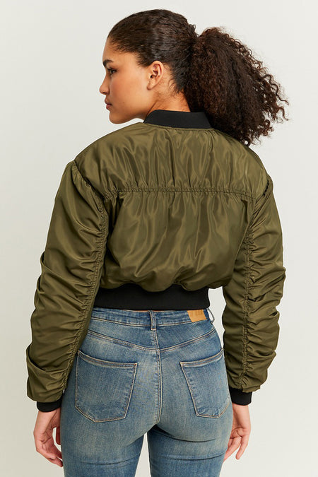 Manteau court vert de TALLY WEIJL, avec des manches froncées, porté sur un jean bleu.