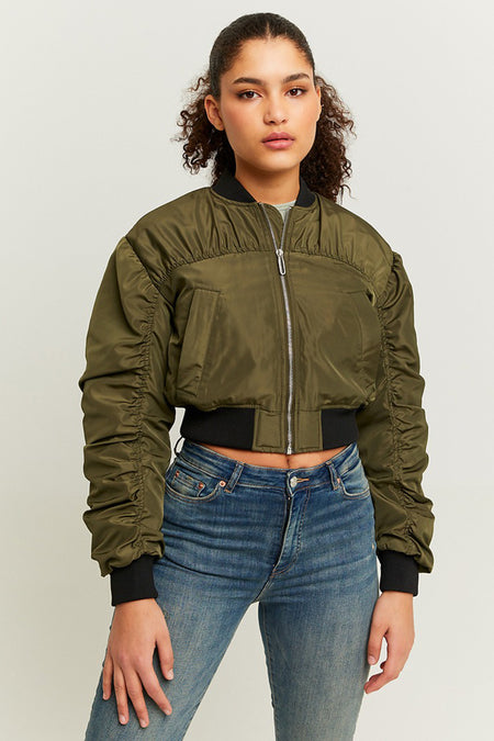 Groene korte jas van TALLY WEIJL, met lange gerimpelde mouwen en een zilverkleurige ritssluiting, gedragen met een blauwe jeans.
