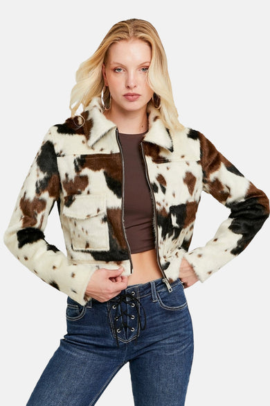Multikleurige jas in imitatieleer van TALLY WEIJL, met koeienprint, gedragen met een bruin shirt en donkere jeans met veters.
