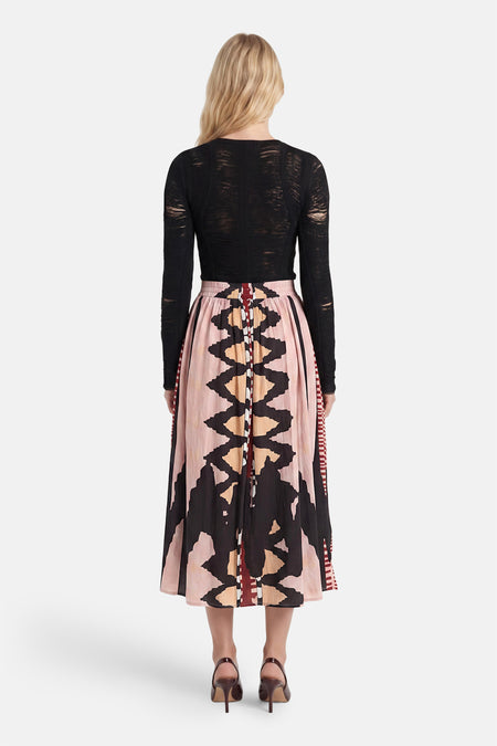 Multicolor lange rok met geometrisch patroon van ADORE, getoond van achteren met zwarte mesh top en bruine hakken