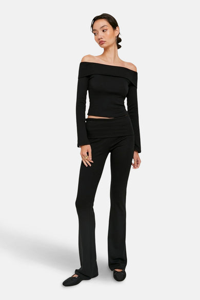 Zwarte broek van TALLY WEIJL, met uitlopende pijpen en gedragen met een zwarte top met blote schouders.
