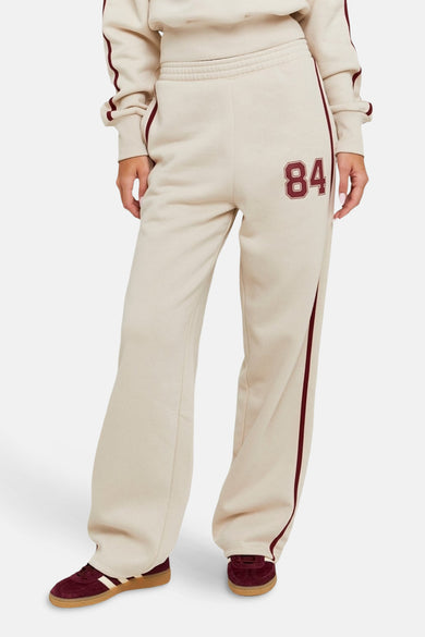 Beige joggingbroek van TALLY WEIJL, met een geborduurd '84' detail en bordeauxrode strepen langs de zijkanten.